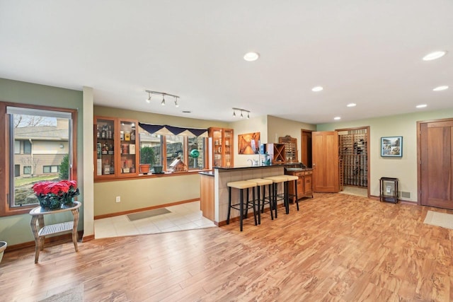 kitchen featuring brown cabinetry, light wood-style floors, a kitchen breakfast bar, and a peninsula