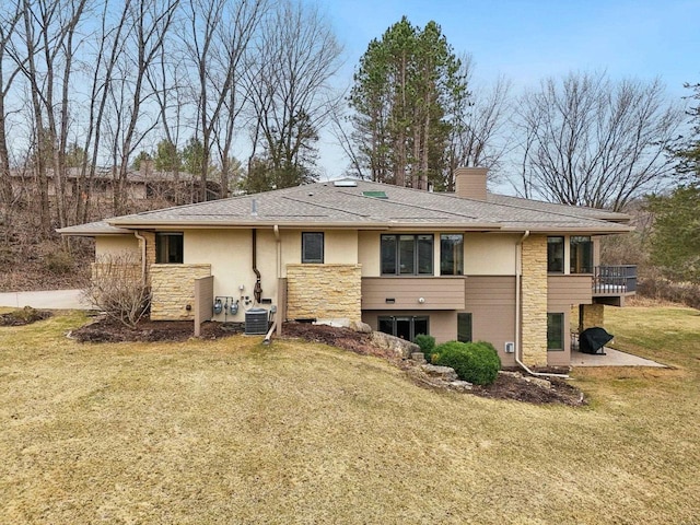 rear view of property with a chimney, stucco siding, stone siding, and a yard