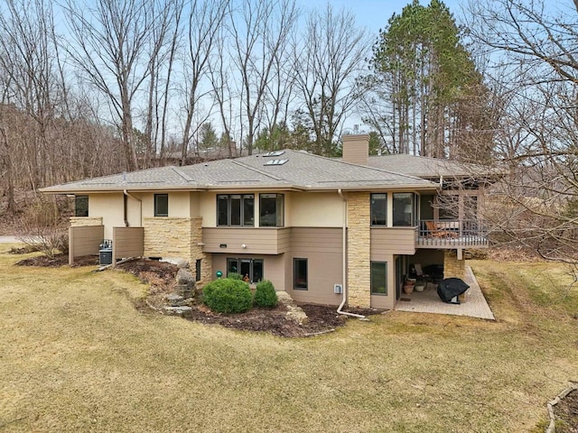 rear view of house with stone siding, a lawn, a patio area, and a chimney