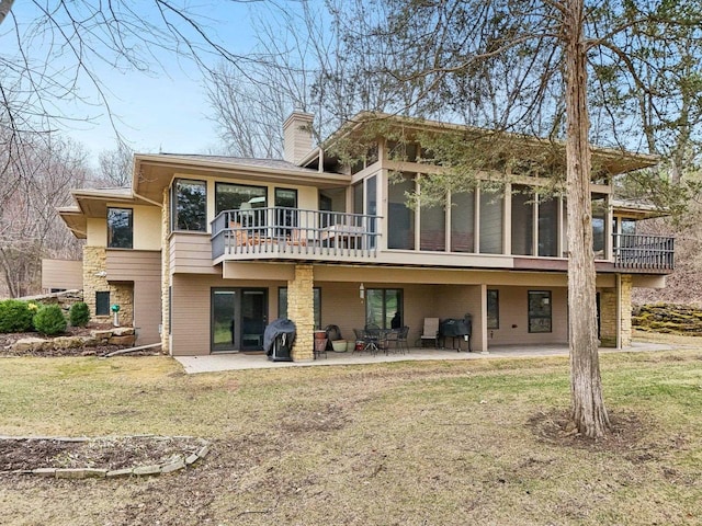 back of house with a chimney, a sunroom, a yard, and a patio area
