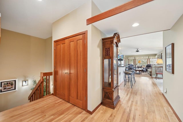 hallway with baseboards, light wood-type flooring, and an upstairs landing