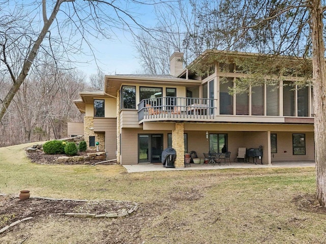 back of property with a lawn, a chimney, a patio, and brick siding