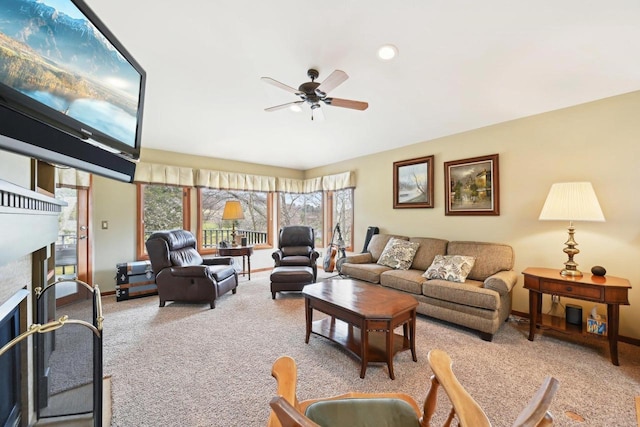 living room with carpet flooring, a ceiling fan, baseboards, and a fireplace