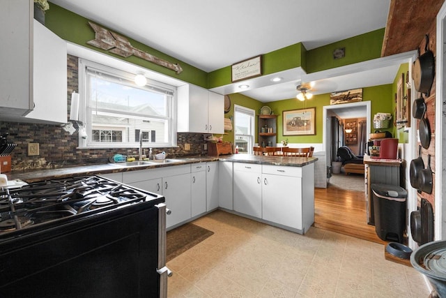 505 S Main St, Edgerton, WI 53534 - kitchen with black gas range oven, a sink, white cabinetry, a peninsula, and dark countertops
