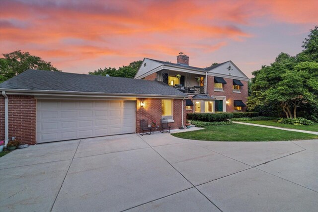 4696 N Lake Dr, Whitefish Bay, WI 53211 - traditional-style home with concrete driveway, a chimney, brick siding, a garage, and a yard