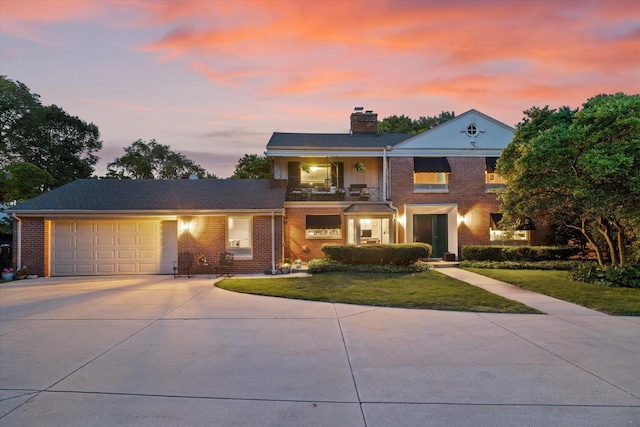 4696 N Lake Dr, Whitefish Bay, WI 53211 - view of front of home with concrete driveway, a balcony, an attached garage, brick siding, and a lawn
