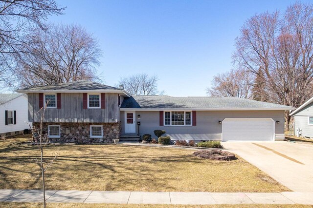 tri-level home with driveway, a garage, and a front lawn
