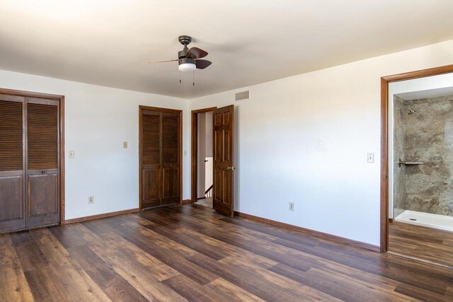 unfurnished bedroom with dark wood-type flooring, baseboards, multiple closets, and visible vents