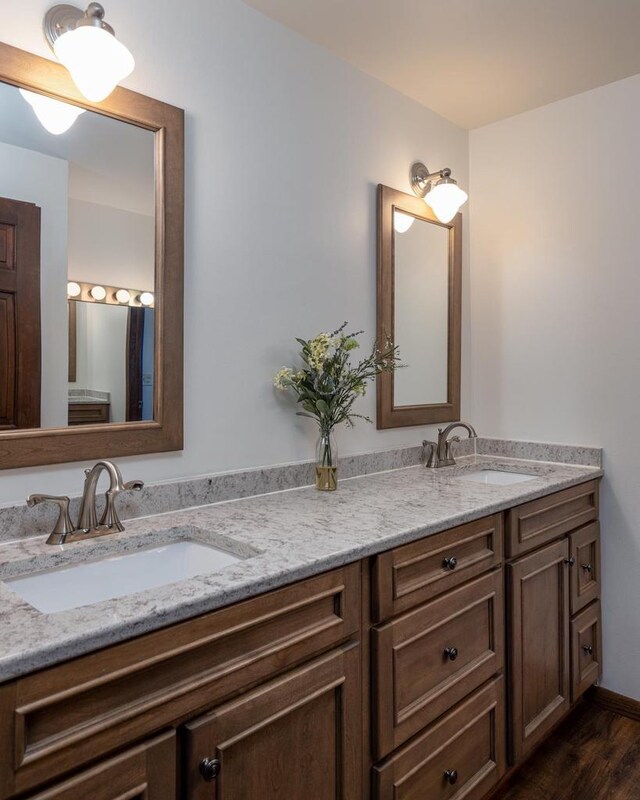 bathroom featuring double vanity, wood finished floors, and a sink