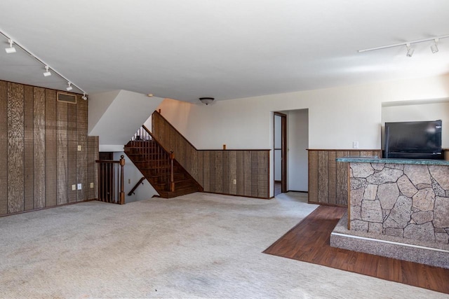 carpeted living area with track lighting, stairway, and visible vents