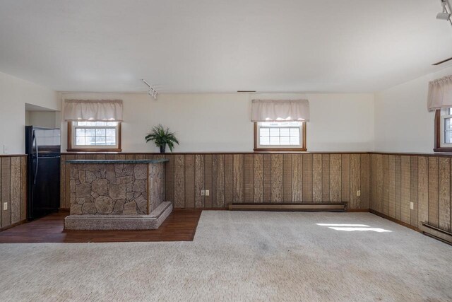 interior space featuring a wainscoted wall, a baseboard heating unit, and a healthy amount of sunlight