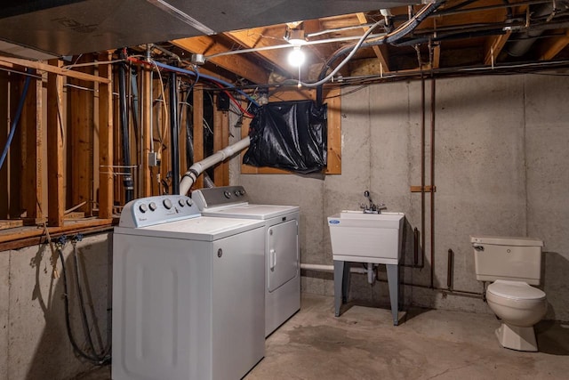 washroom featuring a sink, laundry area, and washer and clothes dryer