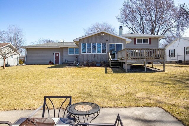 back of house featuring a wooden deck, board and batten siding, and a yard
