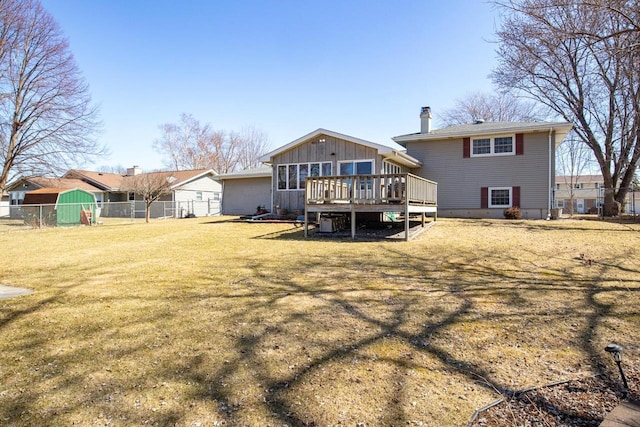 rear view of property with fence, a deck, and a yard