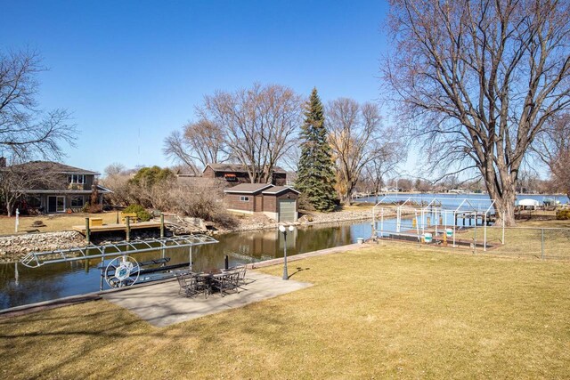 view of dock with a lawn, a water view, and a patio