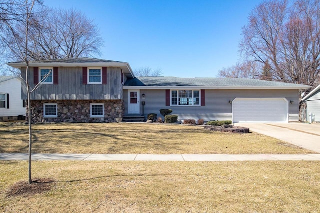 tri-level home with concrete driveway, an attached garage, and a front lawn
