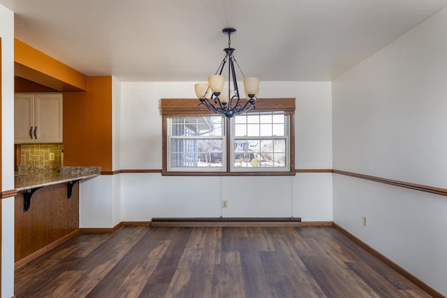 unfurnished dining area featuring baseboards, dark wood-style flooring, a baseboard heating unit, and an inviting chandelier