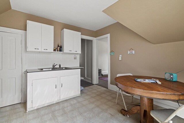 721 N St, Lake Geneva, WI 53147 - kitchen featuring white cabinets, light floors, a sink, open shelves, and vaulted ceiling