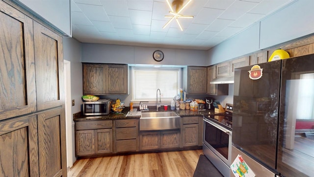 813 Main St, Black River Falls, WI 54615 - kitchen featuring under cabinet range hood, a sink, light wood-style floors, and appliances with stainless steel finishes