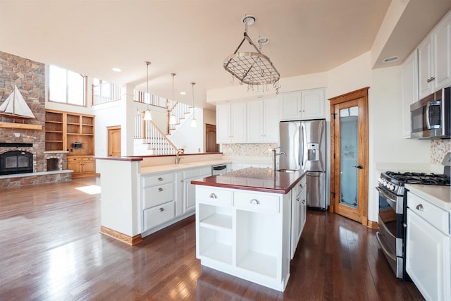 kitchen with stainless steel appliances, an island with sink, open floor plan, and dark wood-type flooring