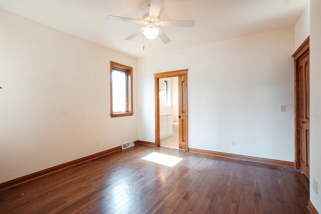spare room with dark wood finished floors, visible vents, baseboards, and ceiling fan