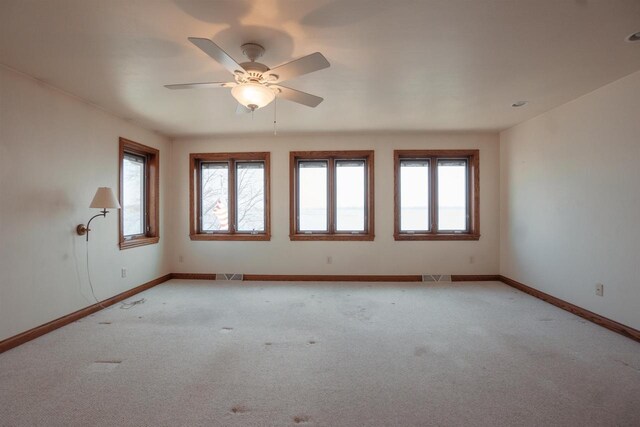 empty room with light colored carpet, plenty of natural light, visible vents, and baseboards