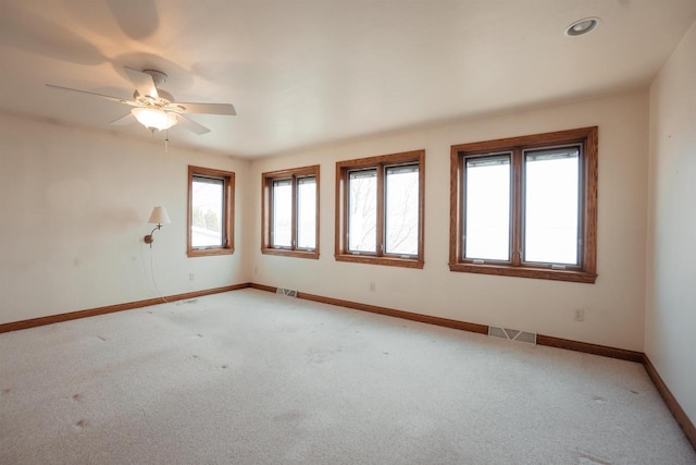 spare room featuring light colored carpet, a wealth of natural light, visible vents, and baseboards