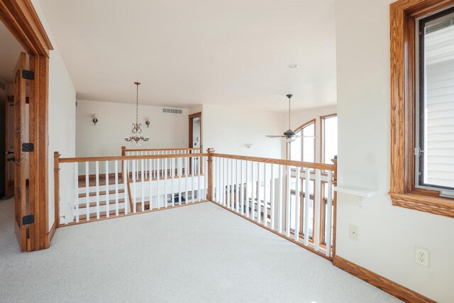 hall with baseboards, an upstairs landing, visible vents, and carpet