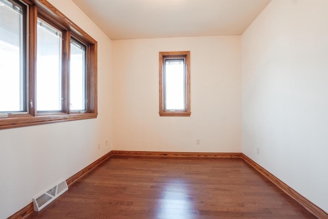 empty room with baseboards, visible vents, and wood finished floors