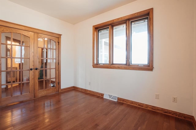 unfurnished room with french doors, visible vents, wood finished floors, and baseboards