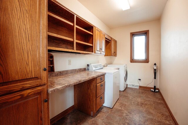 laundry room featuring baseboards, stone finish floor, separate washer and dryer, and cabinet space