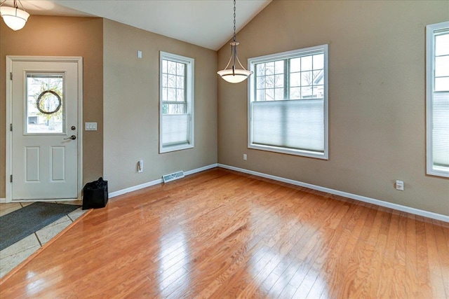 foyer entrance with lofted ceiling, visible vents, wood finished floors, and baseboards