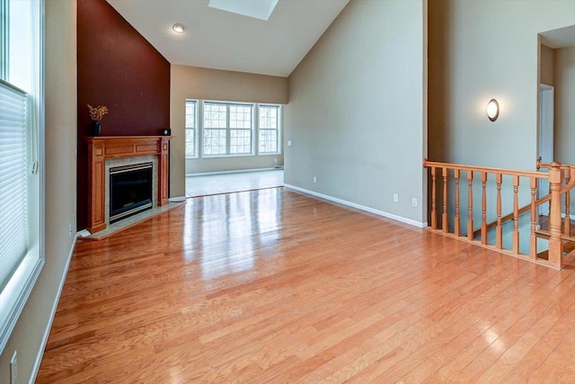 unfurnished living room with a fireplace, wood finished floors, and high vaulted ceiling
