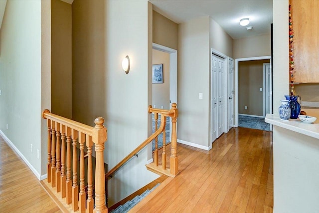 corridor featuring an upstairs landing, hardwood / wood-style floors, and baseboards