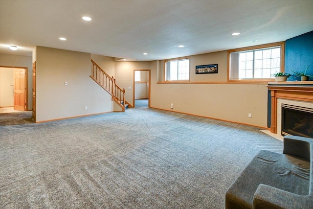 unfurnished living room featuring a tiled fireplace, recessed lighting, baseboards, and stairs