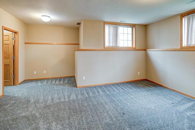 carpeted empty room featuring baseboards and visible vents