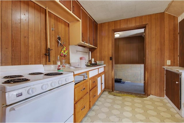 905 Lewis Ave, Cameron, WI 54822 - kitchen with white range with electric stovetop, wood walls, brown cabinetry, and light floors