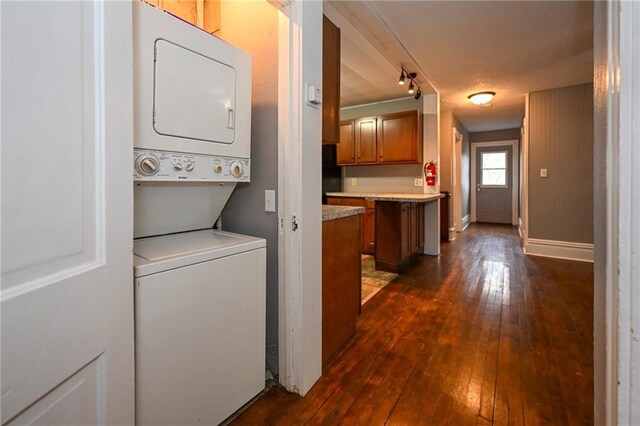 301 Summit St, Spooner, WI 54801 - washroom with dark wood-style floors, stacked washer / drying machine, laundry area, and baseboards