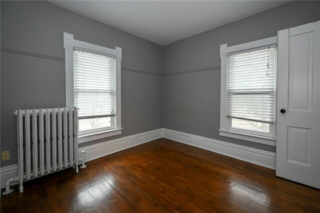 301 Summit St, Spooner, WI 54801 - empty room featuring baseboards, radiator heating unit, and hardwood / wood-style flooring