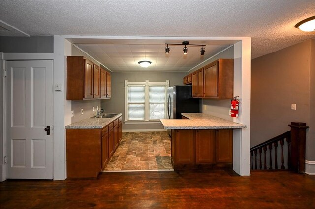 301 Summit St, Spooner, WI 54801 - kitchen with brown cabinets, light countertops, a sink, and freestanding refrigerator