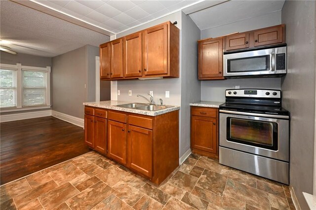 301 Summit St, Spooner, WI 54801 - kitchen featuring light countertops, a sink, appliances with stainless steel finishes, brown cabinetry, and baseboards
