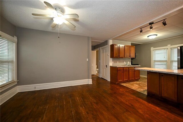 301 Summit St, Spooner, WI 54801 - kitchen with baseboards, dark wood finished floors, a textured ceiling, a ceiling fan, and brown cabinets