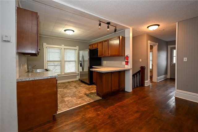 301 Summit St, Spooner, WI 54801 - kitchen with light countertops, brown cabinets, dark wood-type flooring, a sink, and stainless steel refrigerator with ice dispenser