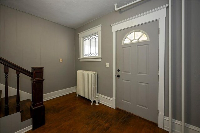 301 Summit St, Spooner, WI 54801 - foyer entrance with baseboards, dark wood-style floors, and radiator heating unit