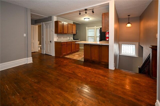 301 Summit St, Spooner, WI 54801 - kitchen with a healthy amount of sunlight, brown cabinets, a textured ceiling, and dark wood-style floors