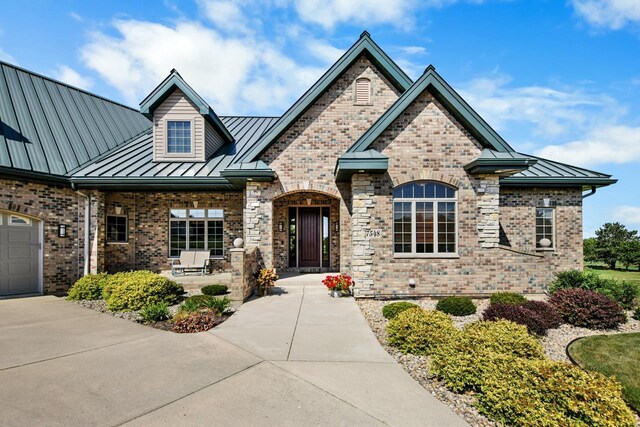 7548 Fallen Oak Dr, Verona, WI 53593 - view of front facade featuring metal roof, a standing seam roof, brick siding, and a porch
