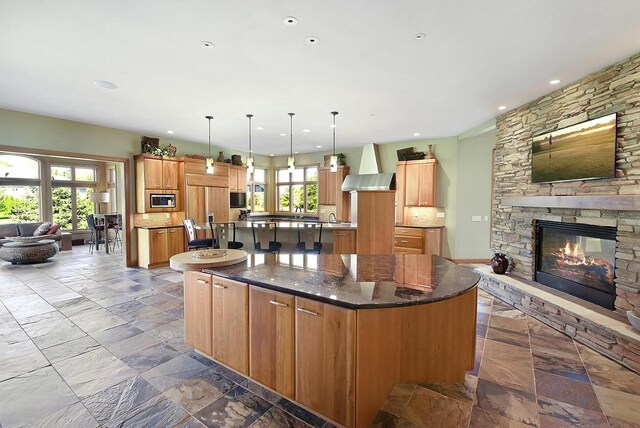 7548 Fallen Oak Dr, Verona, WI 53593 - kitchen with wall chimney exhaust hood, open floor plan, a large island, built in appliances, and stone tile floors