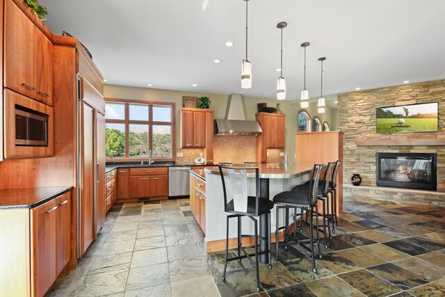 7548 Fallen Oak Dr, Verona, WI 53593 - kitchen featuring wall chimney exhaust hood, stone tile flooring, stainless steel appliances, dark countertops, and decorative backsplash