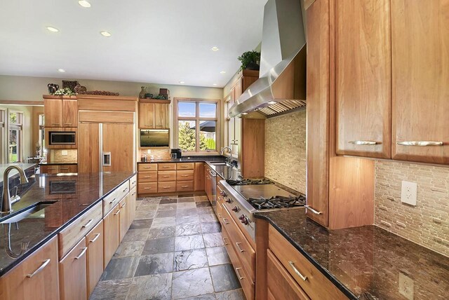 7548 Fallen Oak Dr, Verona, WI 53593 - kitchen featuring wall chimney exhaust hood, tasteful backsplash, a sink, built in appliances, and stone tile floors