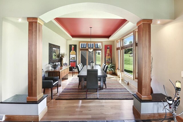 7548 Fallen Oak Dr, Verona, WI 53593 - dining room featuring ornate columns, baseboards, a raised ceiling, arched walkways, and wood finished floors